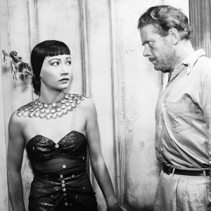 Actress Anna May Wong in a scene from one of her black and white movies, with a white man staring at her menacingly