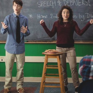 A boy and a girl at the front of a classroom talking to students about the speech and debate club