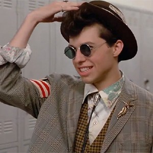 Duckie, from Pretty in Pink, wearing a hat, round sunglasses, a vest, jacket, and bolo tie