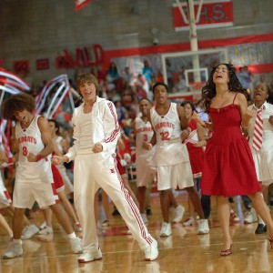 Screen shot from High School Musical with students singing and dancing in the gym