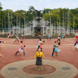 Screenshot from Isn't It Romantic, with Rebel Wilson standing in Central Park surrounded by dancing couples and fountains