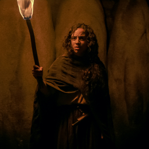 Actress Kiana Madeira wielding a torch and wearing a cape as Sarah Fier in Netflix's Fear Street: Part 3 - 1666