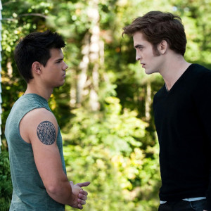 Jacob and Edward from Twilight stare at each other in front of a forest background