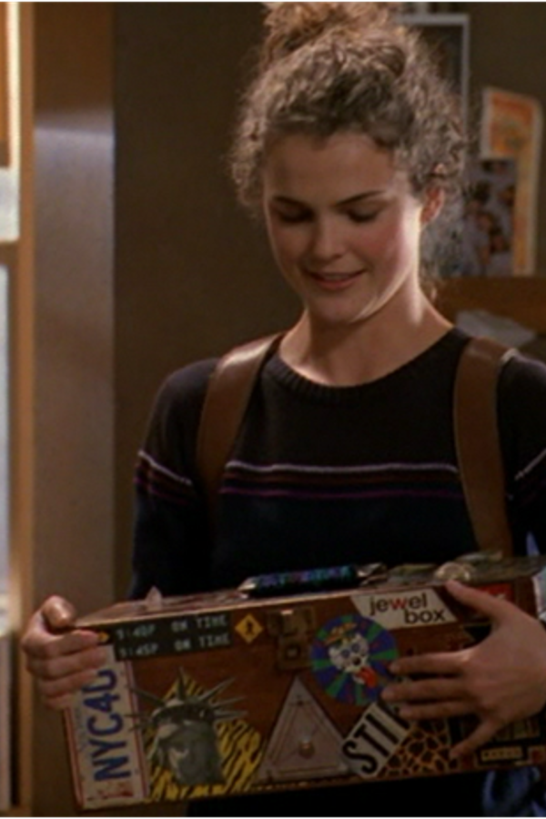 Felicity, smiling and looking down at the box, covered in stickers, that she is holding