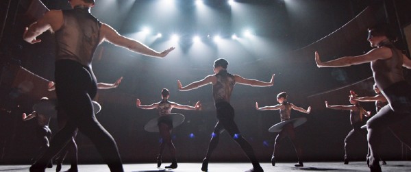 Dancers in black costumes making severe movements on a stage