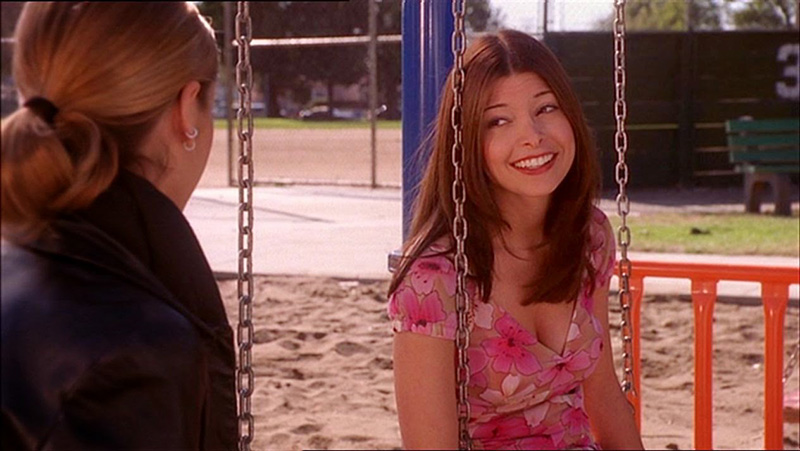April, a pretty brunette human-looking robot, talking to Buffy while sitting in a swing