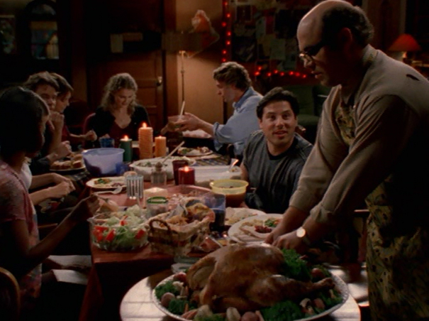 Javier, putting a turkey down on the table where everyone is seated