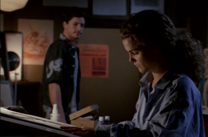 Felicity, drawing on a sketchpad in the art studio as Eli walks behind her