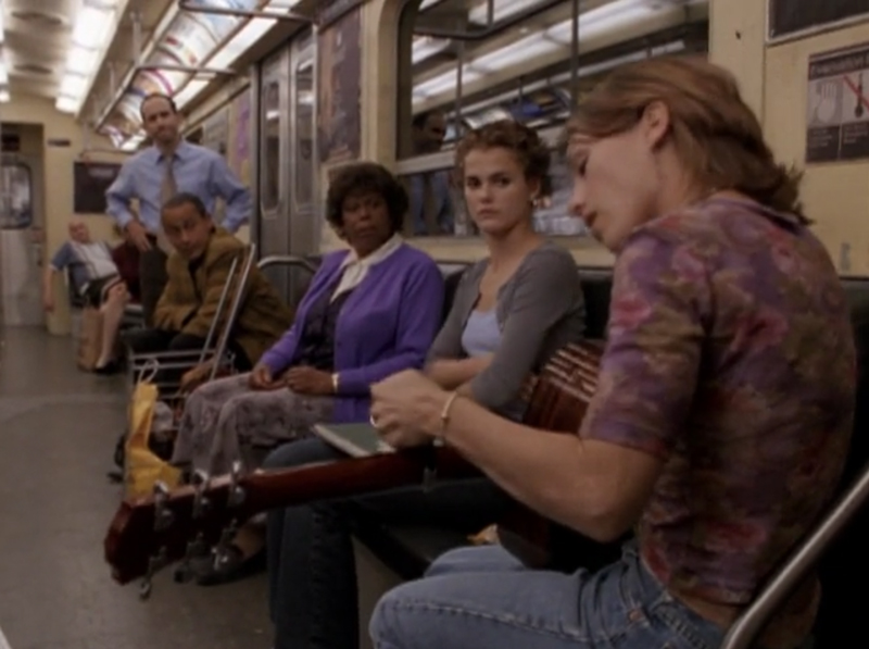 Felicity, with dread in her eyes, watching Julie play guitar in a subway car
