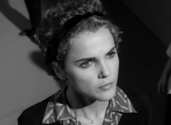 Black and white shot of Felicity, wearing a headband in her short hair and a collared shirt over a sweater