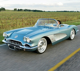 1958 light blue Corvette driving down a road near a field 