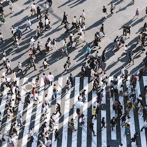 A large crowd of people walk across a street