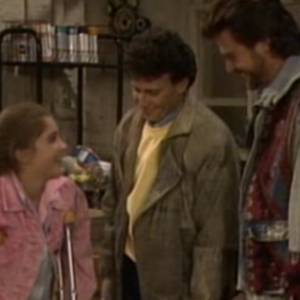 Nicole (Staci Keanan) stands using crutches while Michael (Paul Reiser) and Joey (Greg Evigan) look fondly at her