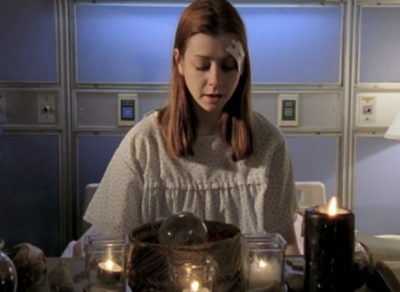 Willow sitting in a hospital bed surrounded by candles