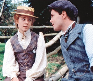 Anne Shirley, wearing a hat, sitting on a fence and giving Gilbert Blythe a WTF look