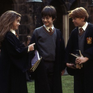 Screenshot of Hermione, Harry, and Ron, wearing their robes and talking outside of Hogwarts