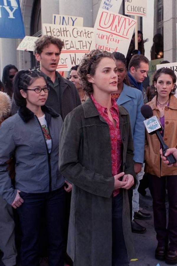 Felicity, with a group of protestors behind her, giving a news interview