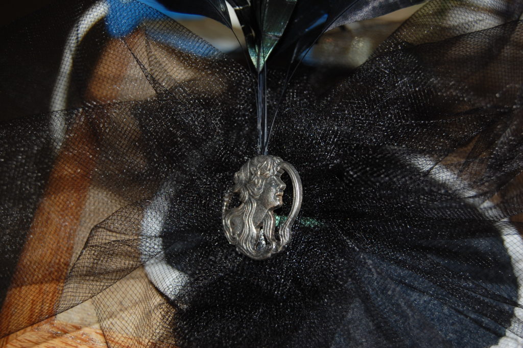 A silver brooch of a woman in profile over a bunch of black tulle