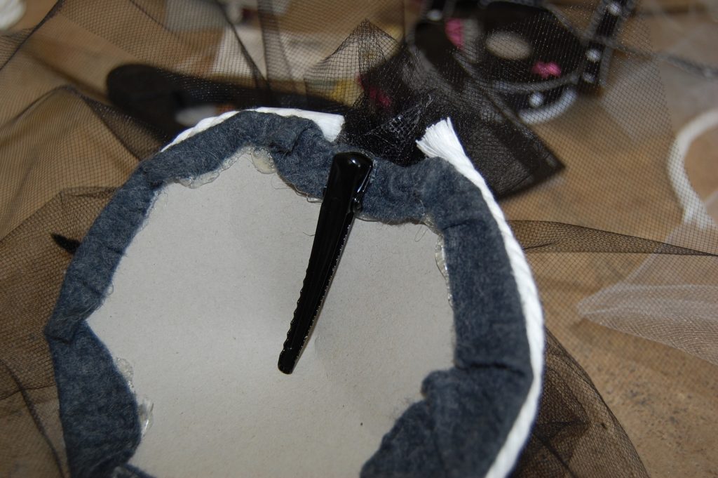 A black alligator clip glued to the underside of the cardboard circle