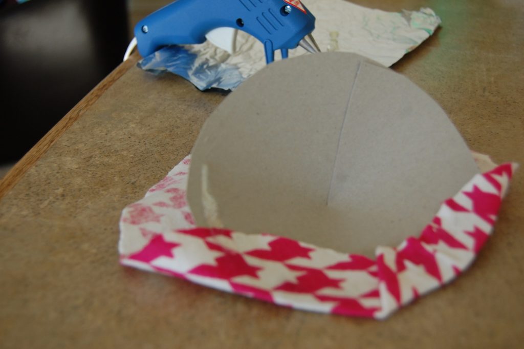 Fabric pulled over the cardboard circle and tucked/glued underneath