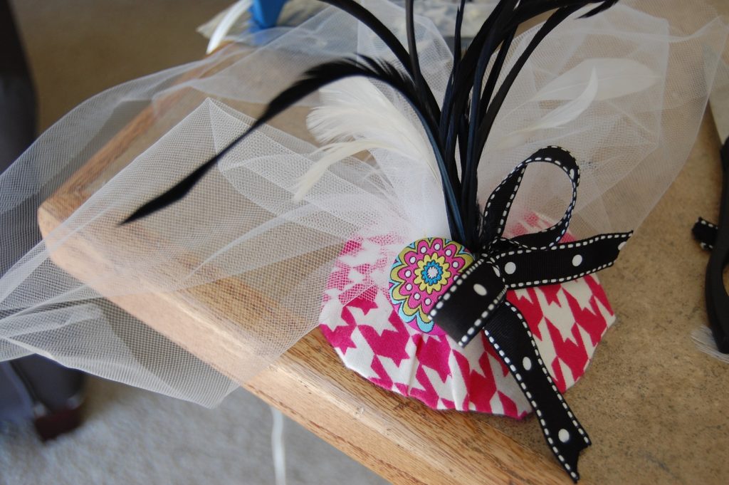 A pink and white houndstooth fascinator with white tulle and black ribbon
