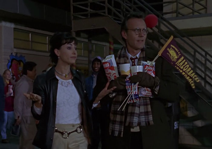 Ms. Calendar standing in the football bleachers with Giles, who is clutching a ton of concessions and two Razorbacks pennants