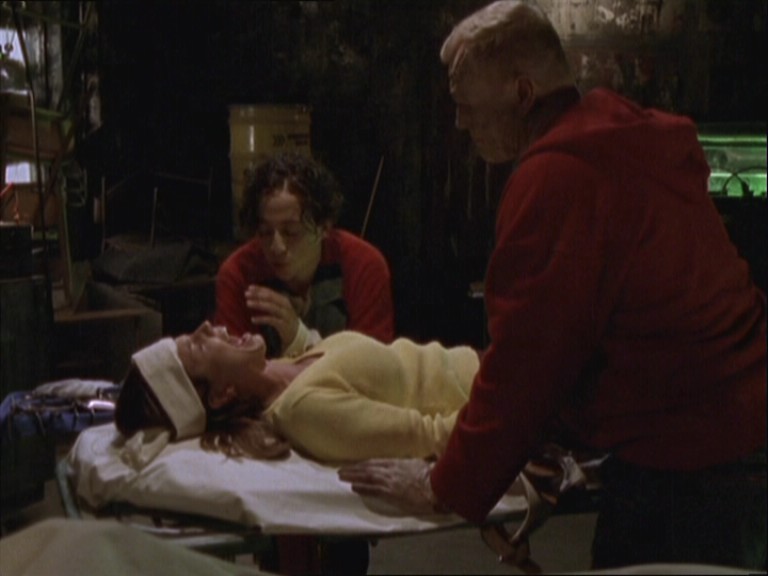 Cordelia, lying on a gurney and screaming while two men loom over her