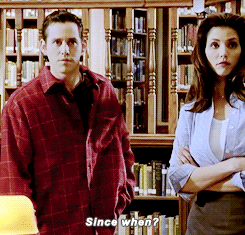 Giles, Xander, and Cordelia are standing in the library when two students walk in