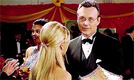 Giles and Buffy talking at prom as Angel approaches in a tux