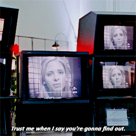 Buffy speaking to a security camera at Walsh, who can see her on the TV screens