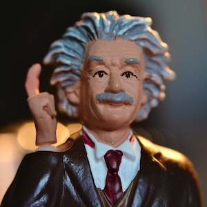 A figurine of Albert Einstein with his right hand raised