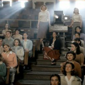 Women sitting in rows in a classroom with a projector in between them