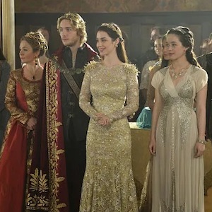 Four people (characters on the show Reign) stand in a line in fancy clothing
