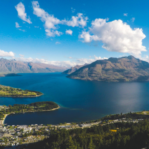 Landscape of New Zealand, with a mountain range in the background and a blue lake surrounded by green land