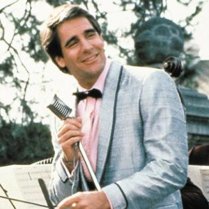 Screenshot from Quantum Leap, with Scott Bakula wearing an old-fashioned suit and holding a retro microphone