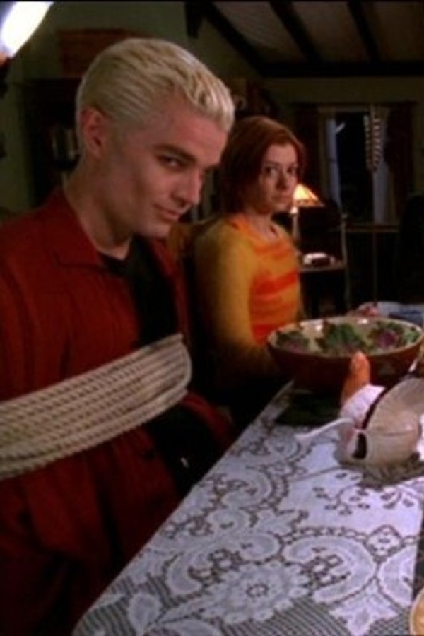 Spike is tied to a chair and sitting next to Willow at the dining table