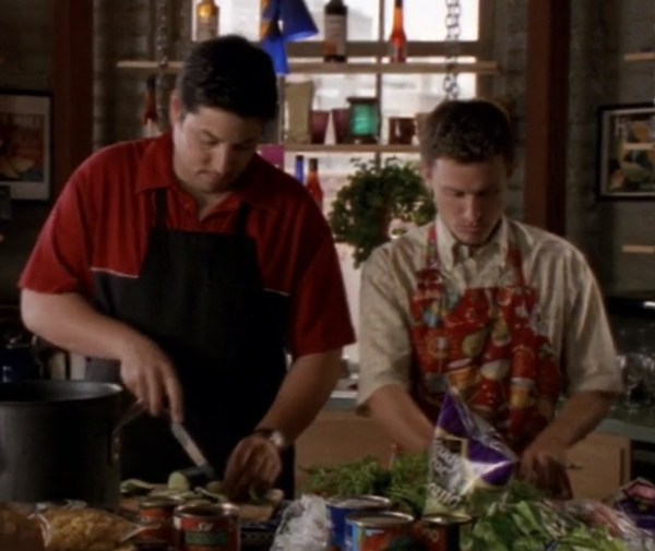 Sean and Richard, side-by-side, wearing aprons and chopping vegetables