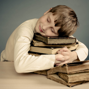 A young boy hugs a pile of books.