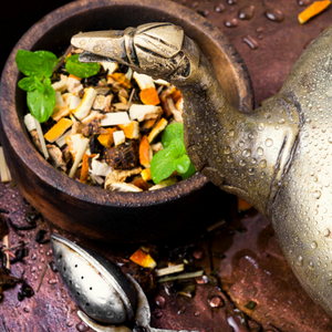 The spout of a teapot and a cup of herbs and such.