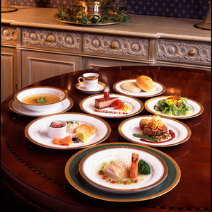 Multiple plates of food on a nice table in a fancy dining room