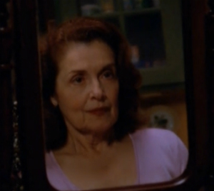 Grams looks at herself in the mirror, pleased with the makeup and darker hair Jen has given her