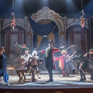 Screenshot from The Greatest Showman, with circus performers on stage hitting their big finish