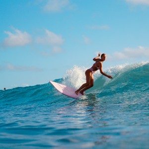 A girl surfing on a blue wave