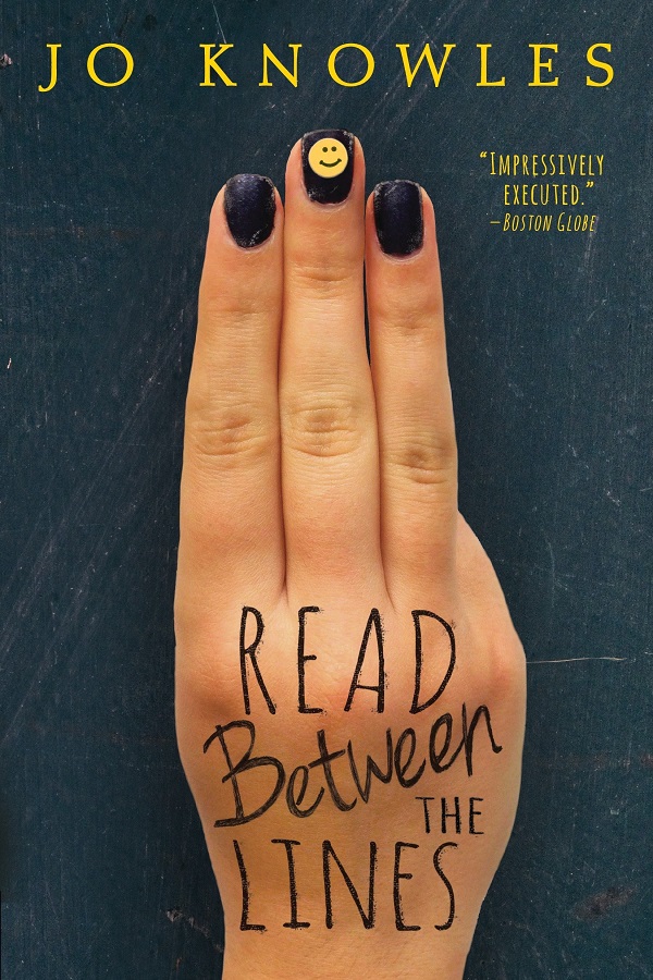 Cover of Read Between the Lines by Jo Knowles. A woman's hand holds up three fingers. Her nails are painted black and the middle one has a smiley face on it.