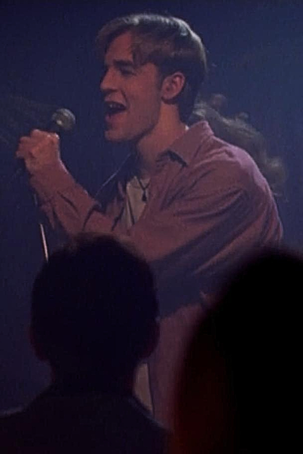 Dawson stands onstage at a nightclub, drunkenly singing into a microphone in front of a crowd