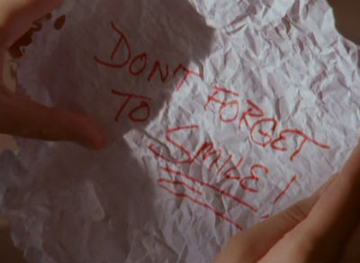 A crumpled note reading, in red, "Don't forget to smile!"