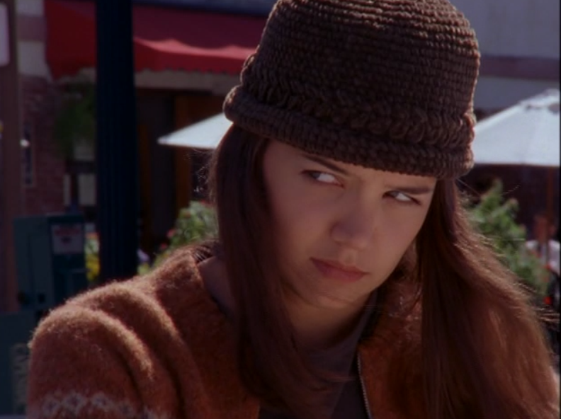Joey wears a brown crocheted bucket hat and a supremely scornful look on her face