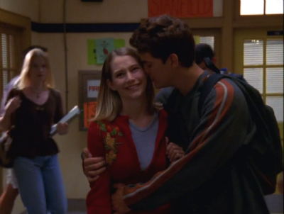 Pacey hugs a smiling Andie and kisses her on the cheek as they walk down the hallway