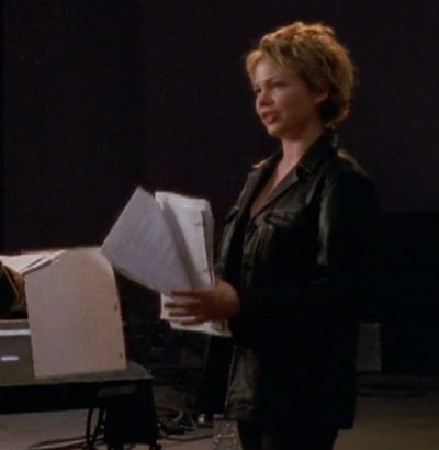 Jen stands onstage wearing a heinous black leather duster jacket