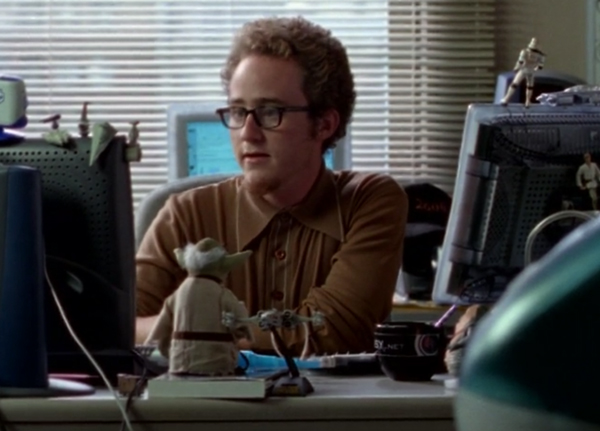 Matt Doherty, a white guy with glasses and curly hair, sitting at a desk with computer and Star Wars stuff
